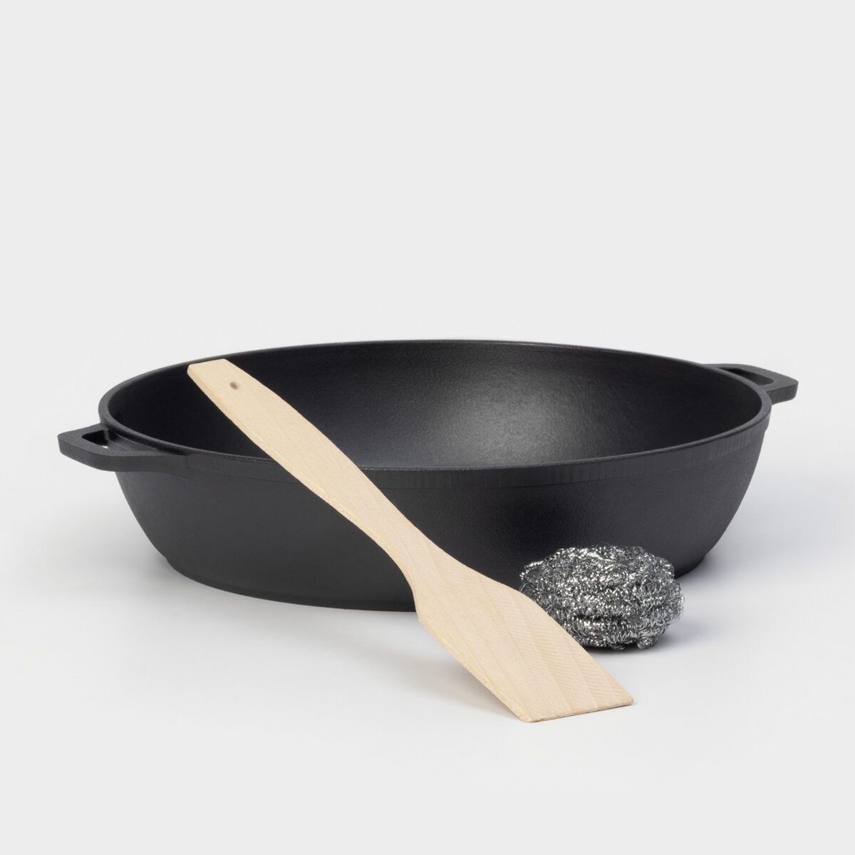 Чугунная жаровня 28 см для запекания и готовки на 4 литра — лучшее тепло распределение Чугунная жаровня с двумя ручками, диаметром 28 см, объемом 4 литра, с деревянной лопаткой и металлической губкой на белом фоне