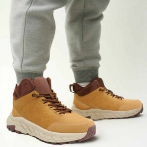 Желто-коричневые ботинки FILA с контрастной подошвой и логотипом, надетые на человека в спортивных штанах