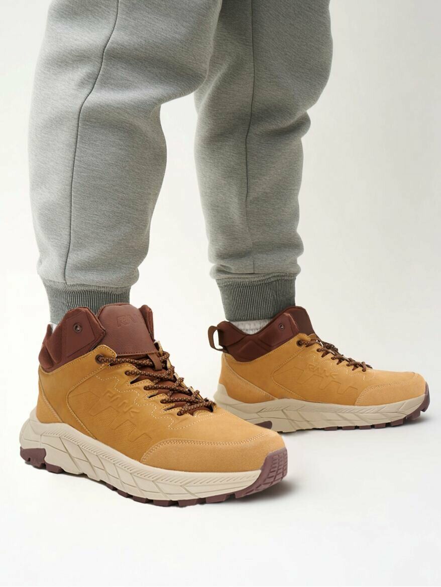 Желто-коричневые ботинки FILA с контрастной подошвой и логотипом, надетые на человека в спортивных штанах