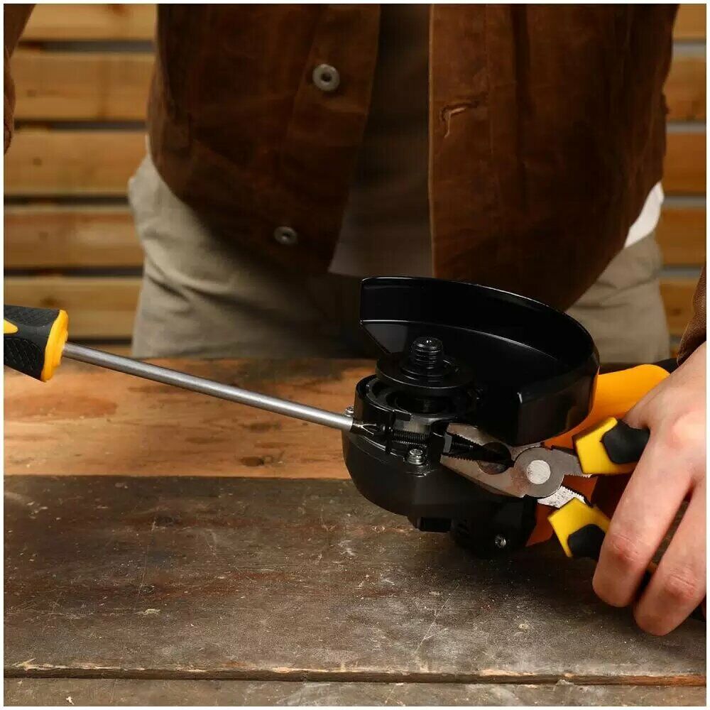 Человек обслуживает дисковую шлифовальную машину, используя плоскогубцы и отвертку на деревянной рабочей поверхности