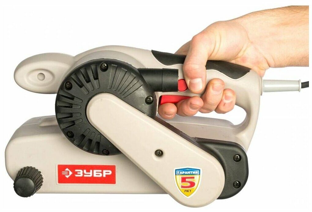 Ручной ленточный шлифовальный станок Зубр с красной кнопкой включения, эргономичными рукоятками и регулятором натяжения ленты