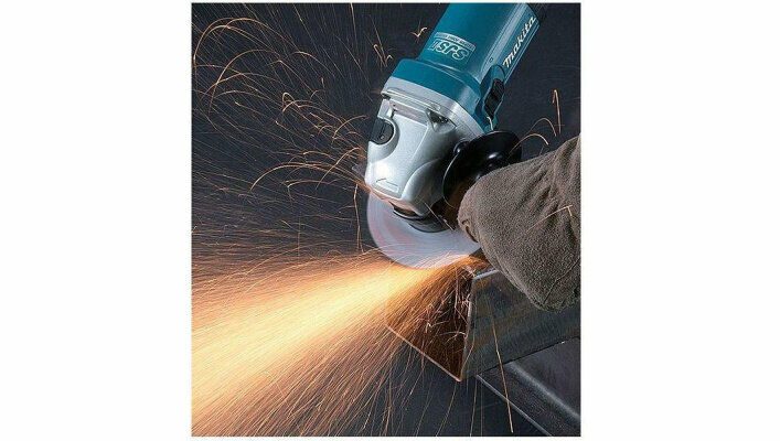 Человек использует углошлифовальную машину Makita с боковой ручкой для обработки металлической детали, от которой летят искры