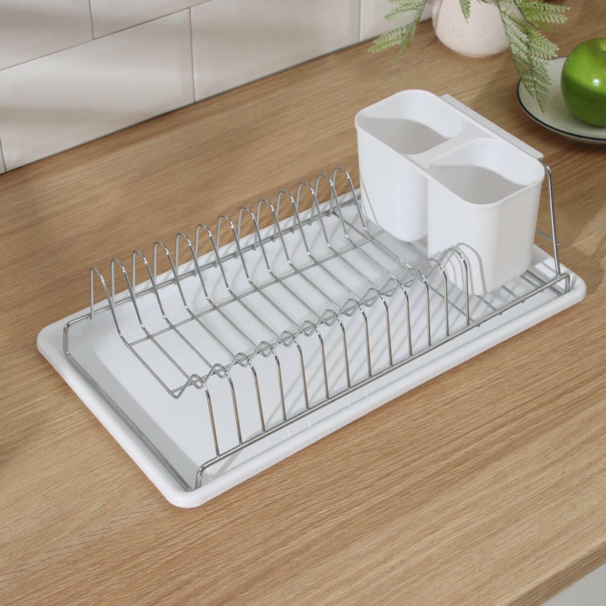 Металлическая настольная сушилка для посуды с поддоном и секцией для столовых приборов Настольная металлическая двухъярусная сушилка для посуды с белым поддоном и держателем для столовых приборов на деревянной столешнице