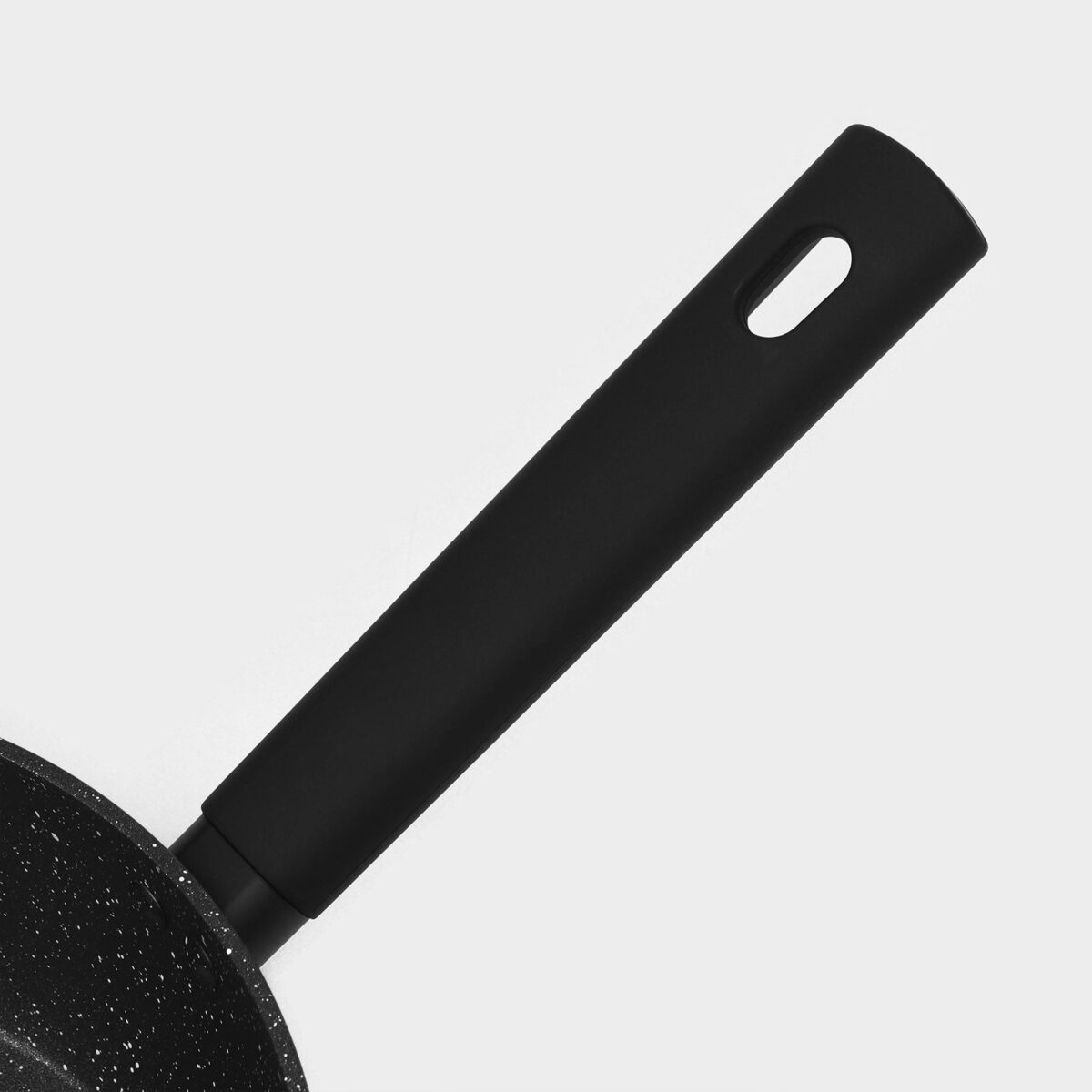 Чёрная антипригарная сковорода с толстыми стенками и удобной рукояткой для подвешивания Частичный вид чёрной антипригарной сковороды с овальной рукояткой и краем с покрытием с каменной текстурой