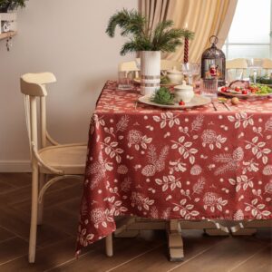 Скатерть рогожка бордового цвета с новогодним растительным узором, аккуратно застеленной на столе в светлой комнате