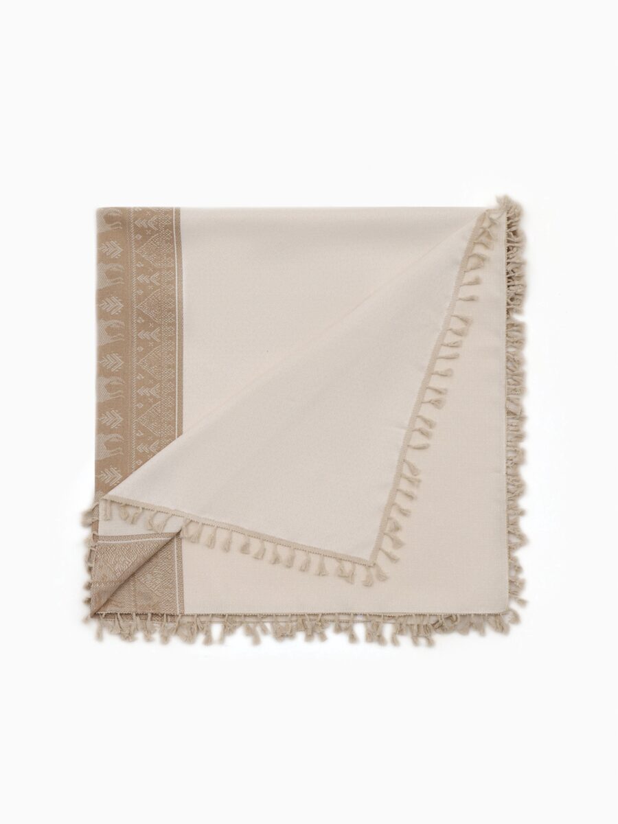 Новогодняя бежевая скатерть с рисунком оленей, бахромой и геометрическим узором – текстиль для праздничного стола Светлая бежевая скатерть с изображением оленей, украшенная бахромой и новогодним орнаментом, прямоугольная форма