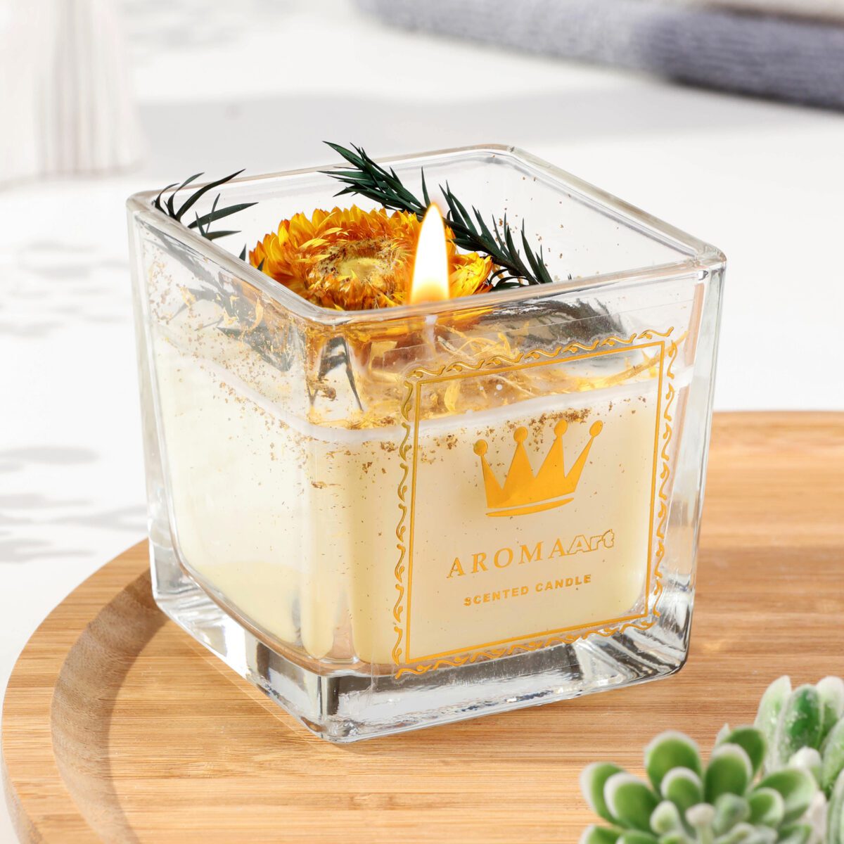 Ароматическая свеча в стеклянной квадратной банке с сушеным цветком и зеленью на фоне уютного интерьера