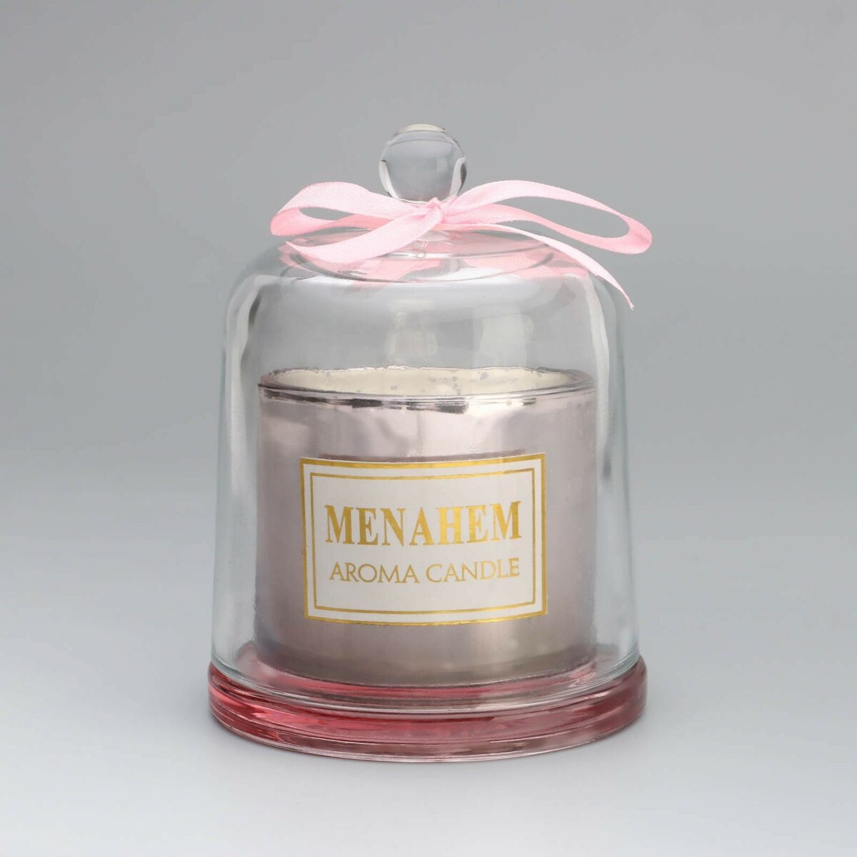 Ароматическая свеча в прозрачном стеклянном колпаке с золотистой этикеткой – стильное и элегантное дополнение к интерьеру Ароматическая свеча для дома в стеклянном колпаке с розовым бантом, золотистой этикеткой и светло-серебристым основанием