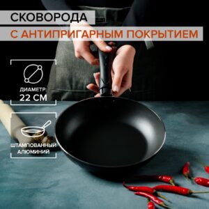 Бордовая сковорода из алюминия с антипригарным покрытием и черной эргономичной ручкой на кухонном столе
