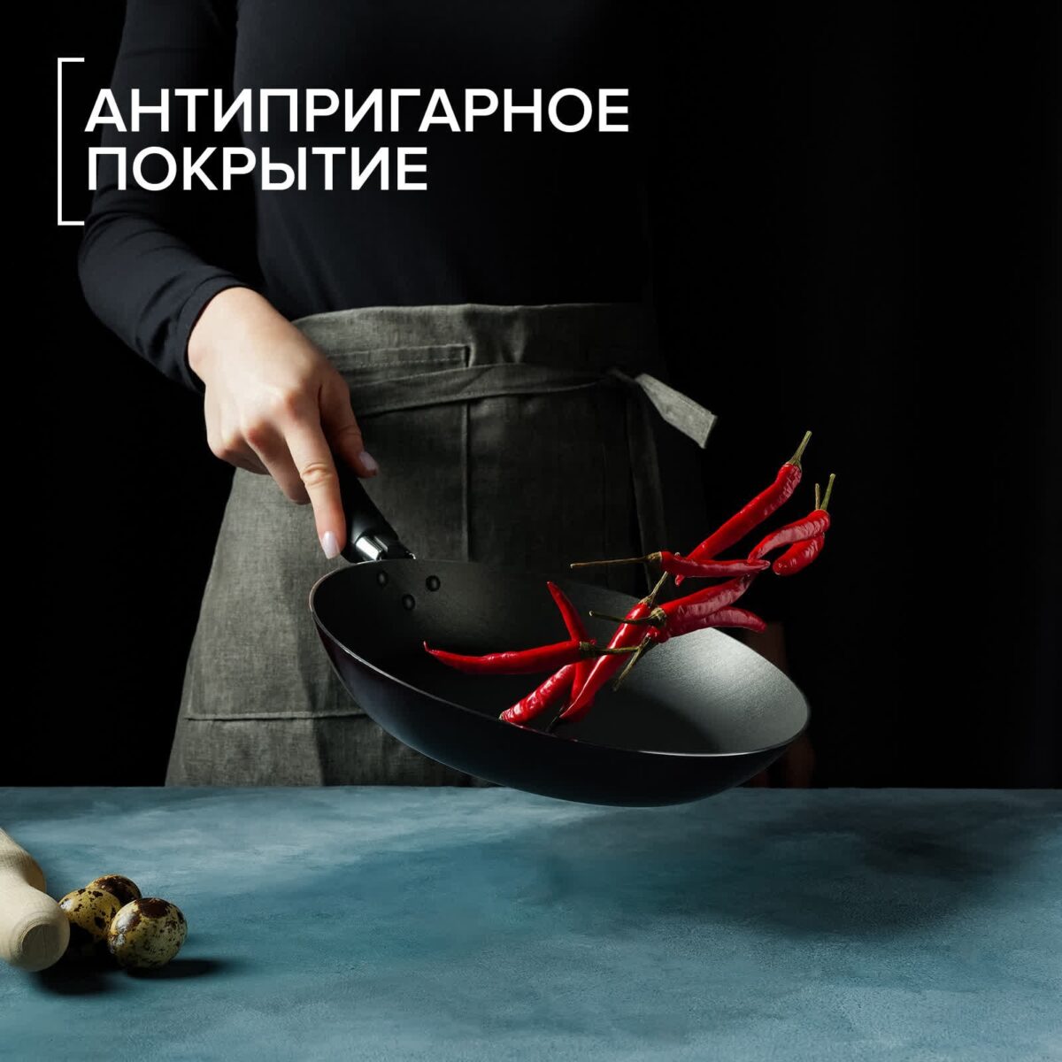 Сковорода из алюминия с антипригарным покрытием для профессиональной готовки Глубокая алюминиевая сковорода с антипригарным покрытием, человек держит ее на фоне кухни с подкинутыми красными перцами чили